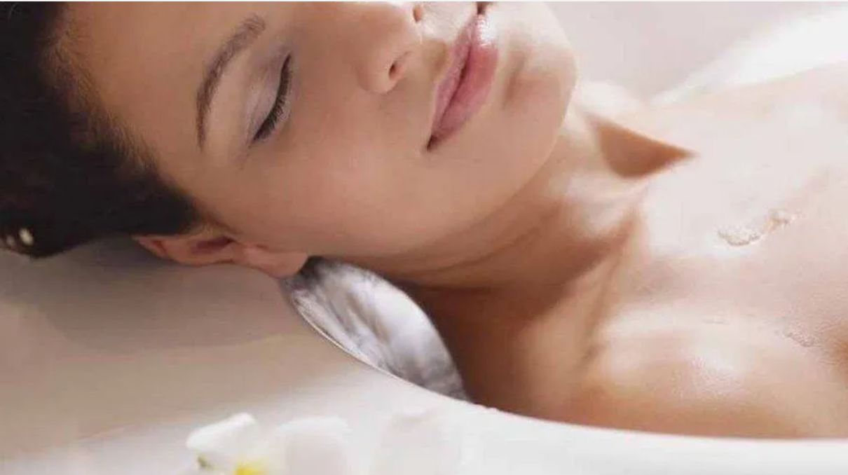 Junge Frau entspannt in der Badewanne mit Kissen